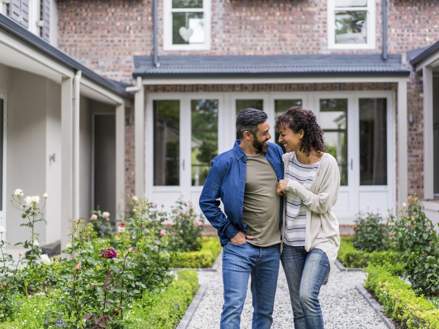 Smiling couple walking outside the front of their new home.